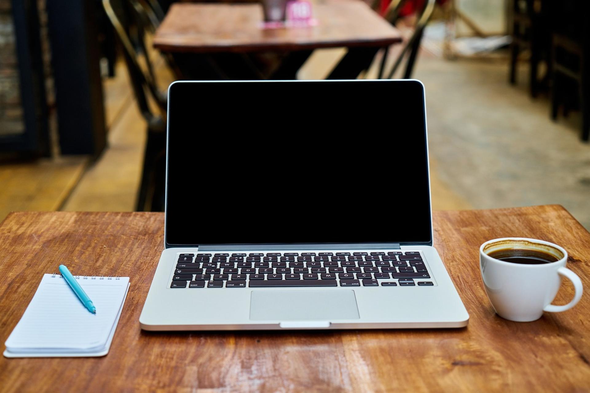 Laptop, Notizblock und Kaffeetasse