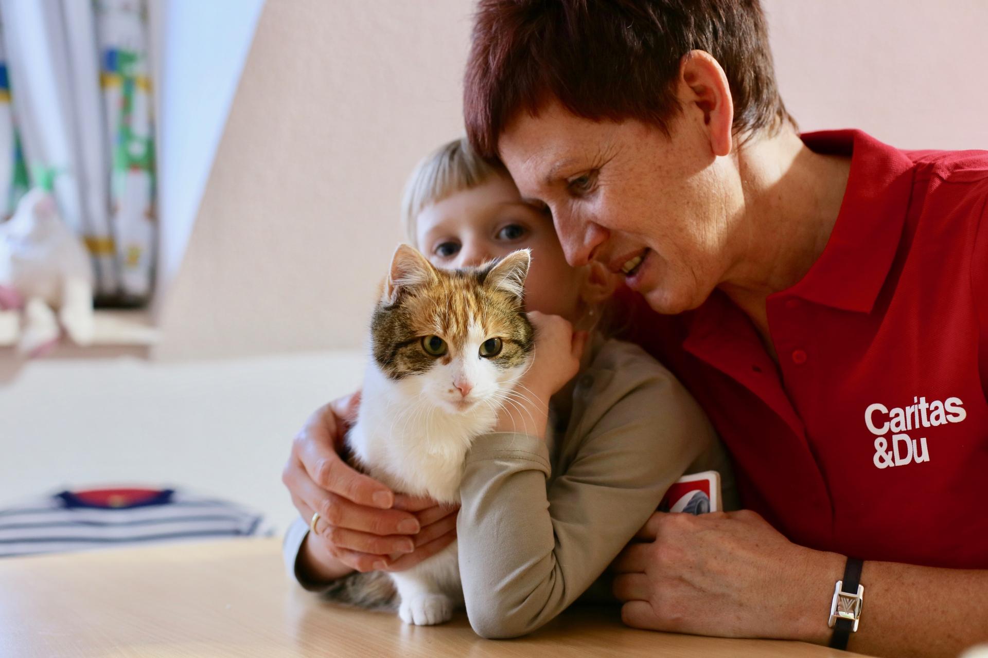 Caritas-Mitarbeiterin gemeinsam mit Kind und Katze