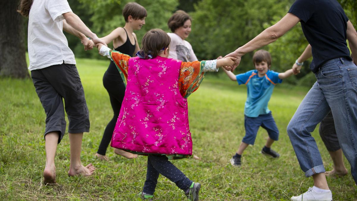 Kinder und Eltern, die auf einer Wiese im Kreis laufen